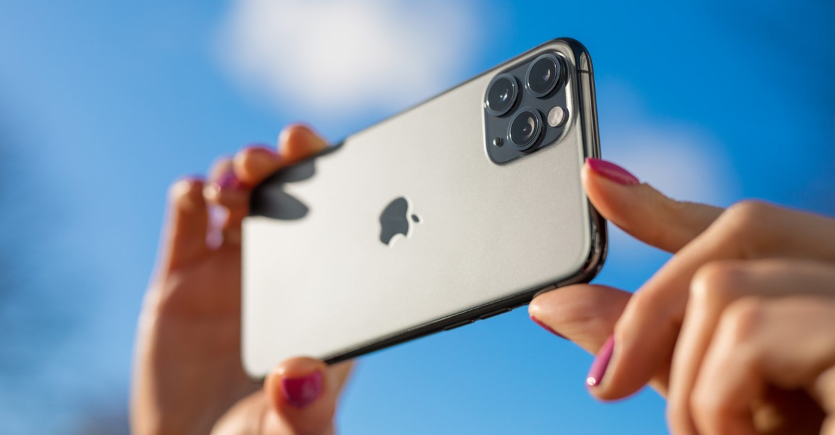 Hand holding iPhone to take photos outside.